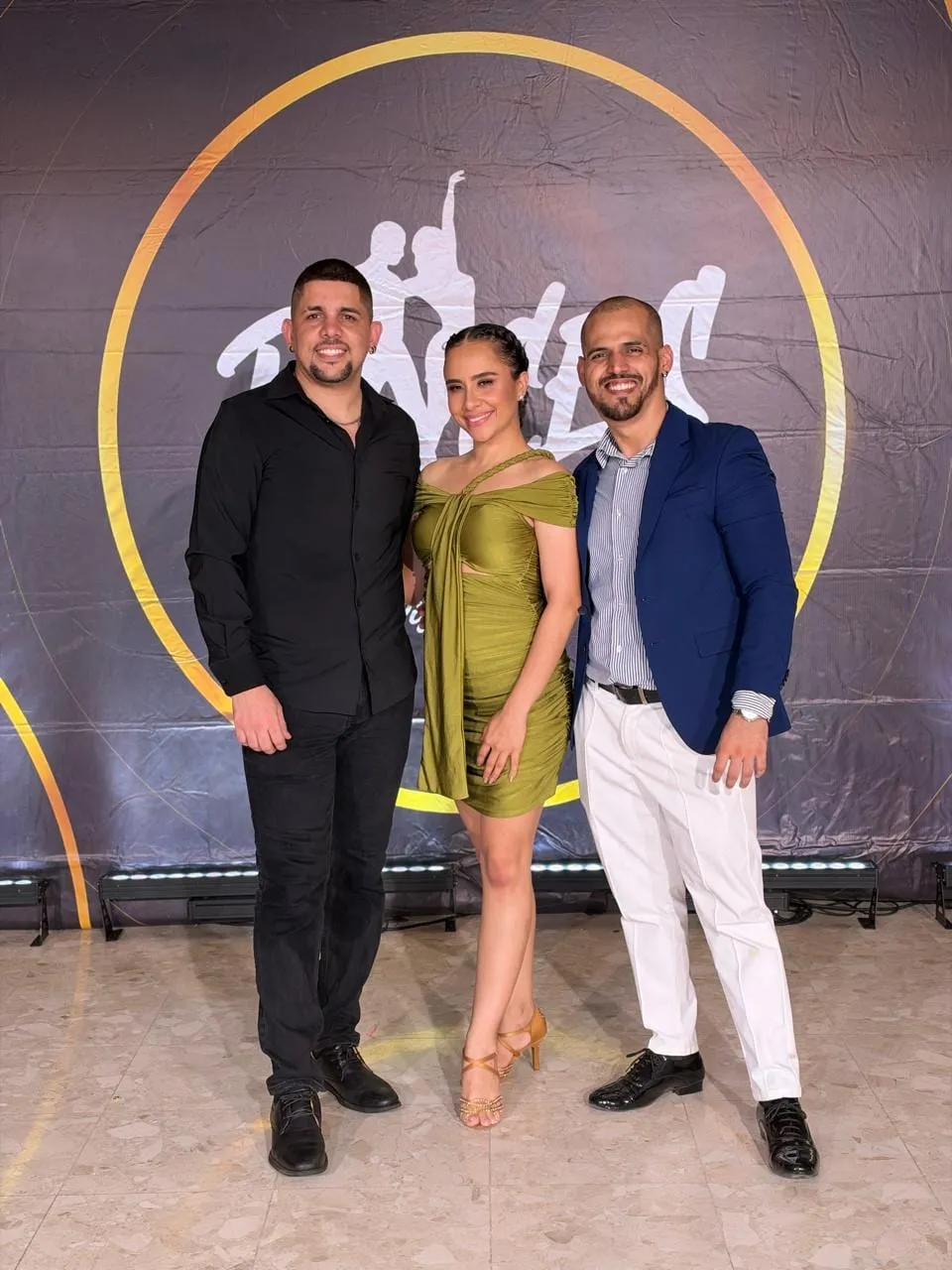Los tres directores de Raíces, de pie frente a un fondo con el logo de la escuela